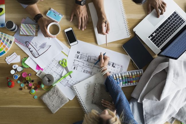 Overhead view of architects and designers reviewing blueprints